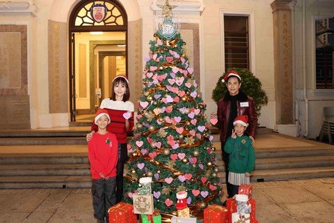 保良局庞董晶怡主席(后排左)与「保良局儿童助养大使」郑嘉颖(后排右)及住宿儿童为圣诞树挂上祝福心意卡。